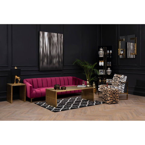 A luxurious three-seat sofa upholstered in rich wine-colored velvet, featuring a tufted backrest and elegant armrests. The sofa is positioned in a stylish living room setting with dark walls, a patterned black and white rug, a wooden coffee table, and decorative accessories, including a plant and artwork on the walls