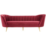 Three-seat sofa upholstered in rich wine-colored velvet, featuring a channel-tufted backrest and sleek, angled arms. The sofa stands on slender gold metal legs, adding a touch of elegance to its modern design