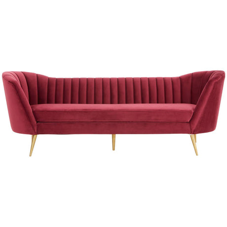 Three-seat sofa upholstered in rich wine-colored velvet, featuring a channel-tufted backrest and sleek, angled arms. The sofa stands on slender gold metal legs, adding a touch of elegance to its modern design