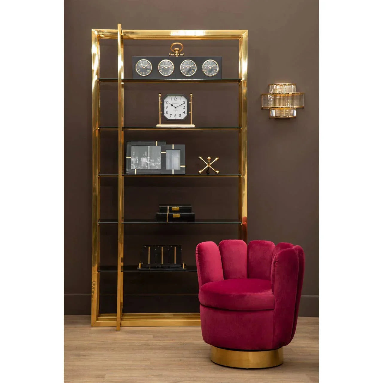 Gold metal shelving unit with glass shelves and red velvet accent chair in modern living room