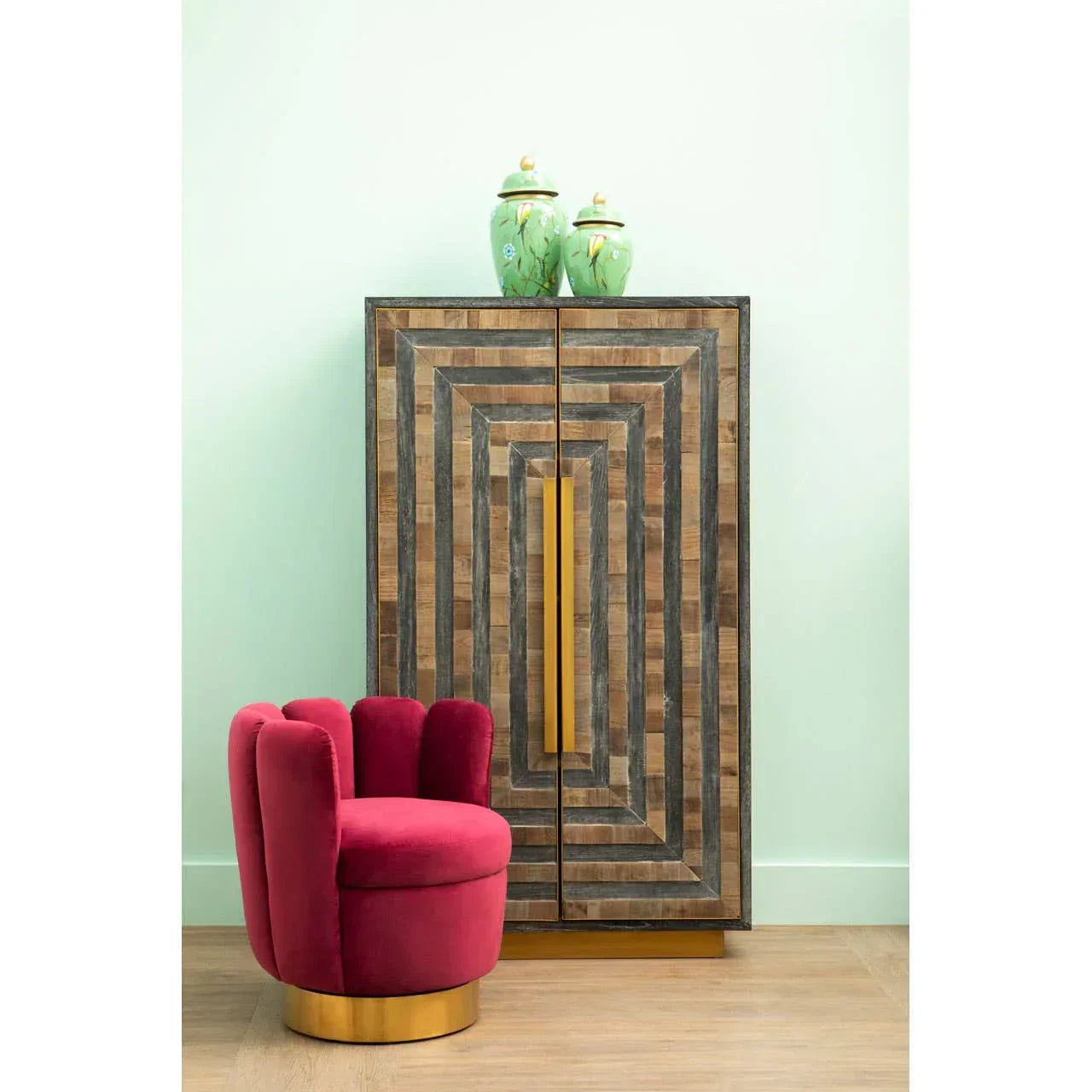 Velvet accent chair with gold base beside geometric wood cabinet and green decorative jars