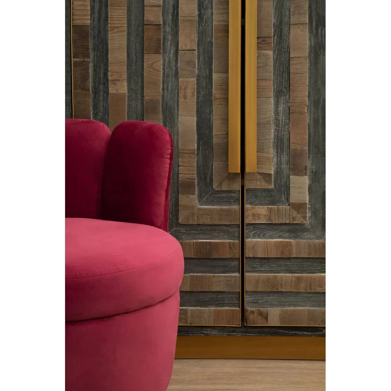 Red velvet armchair beside geometric wood and metal sideboard with gold handles