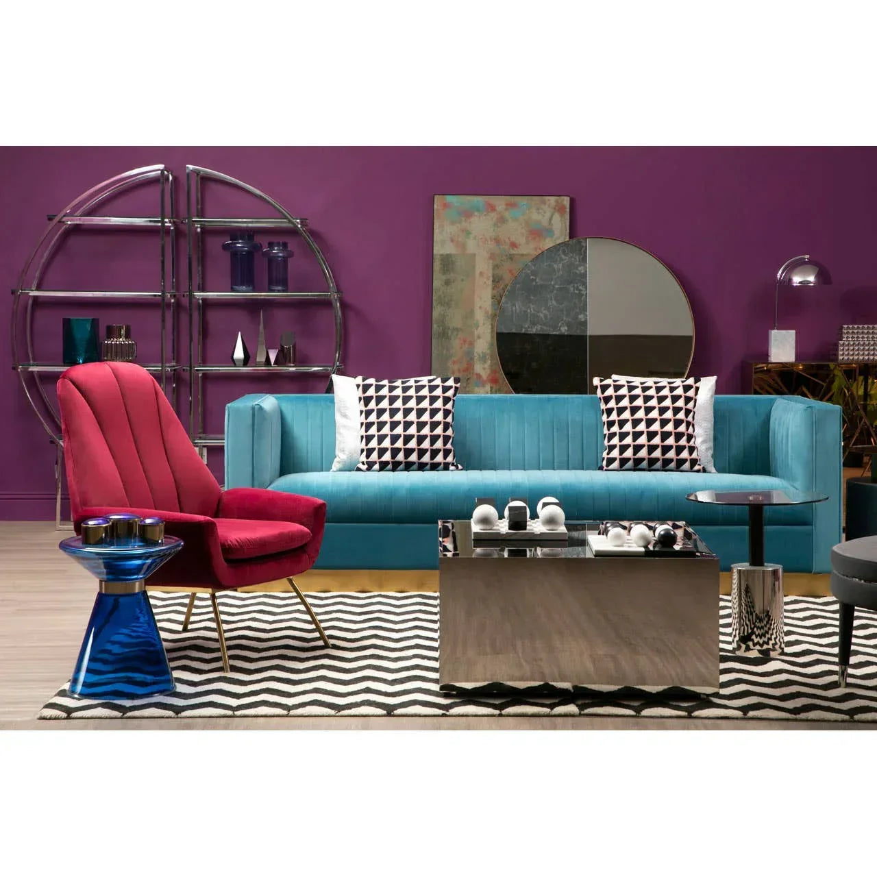 Blue velvet sofa with geometric cushions and red accent chair in modern living room setup