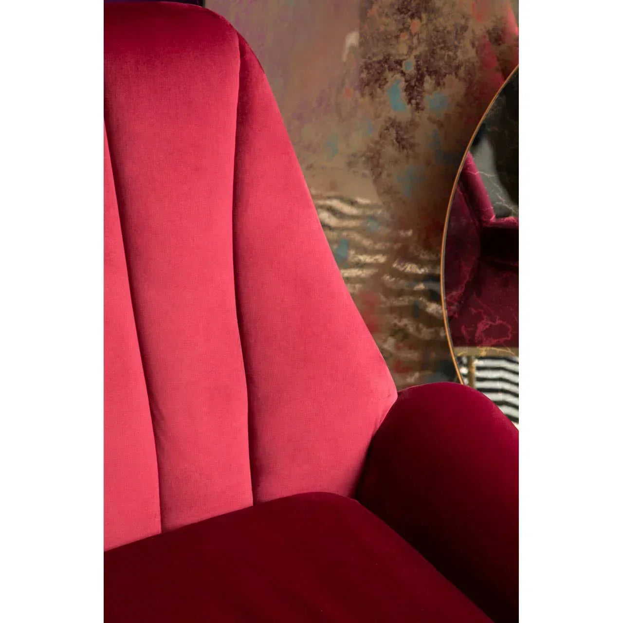 Velvet armchair in deep red with panelled backrest and soft upholstery, close up view