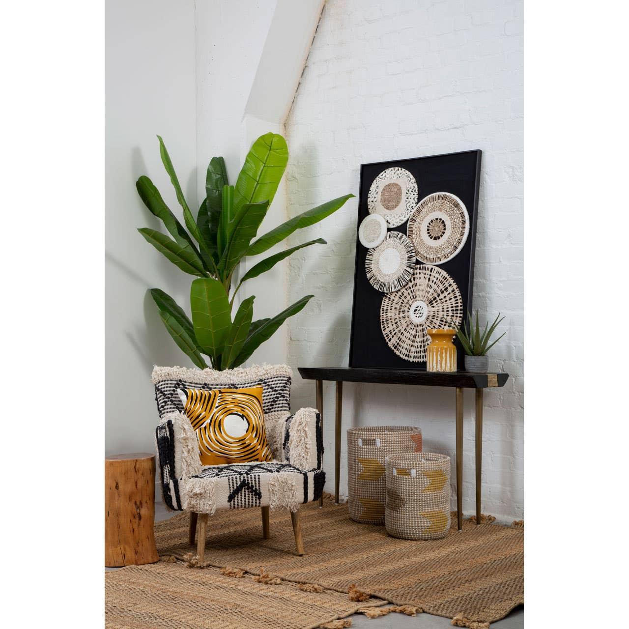 Modern accent chair with textured upholstery, patterned cushion, indoor plant, and woven baskets