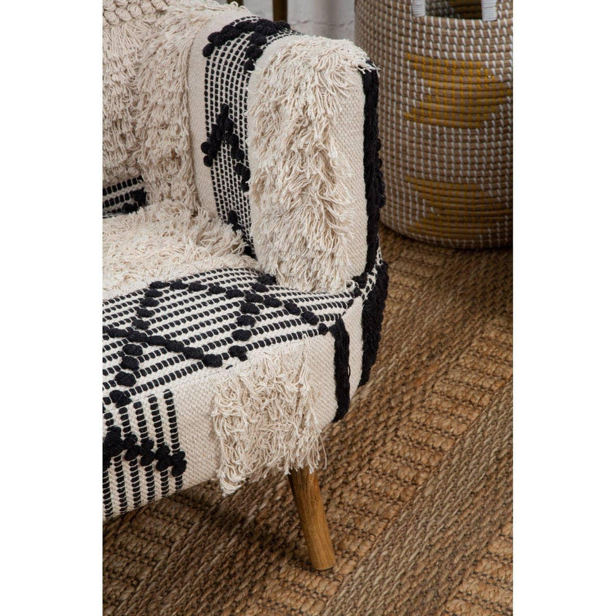 Textured armchair with black and cream geometric upholstery and wooden legs on woven rug