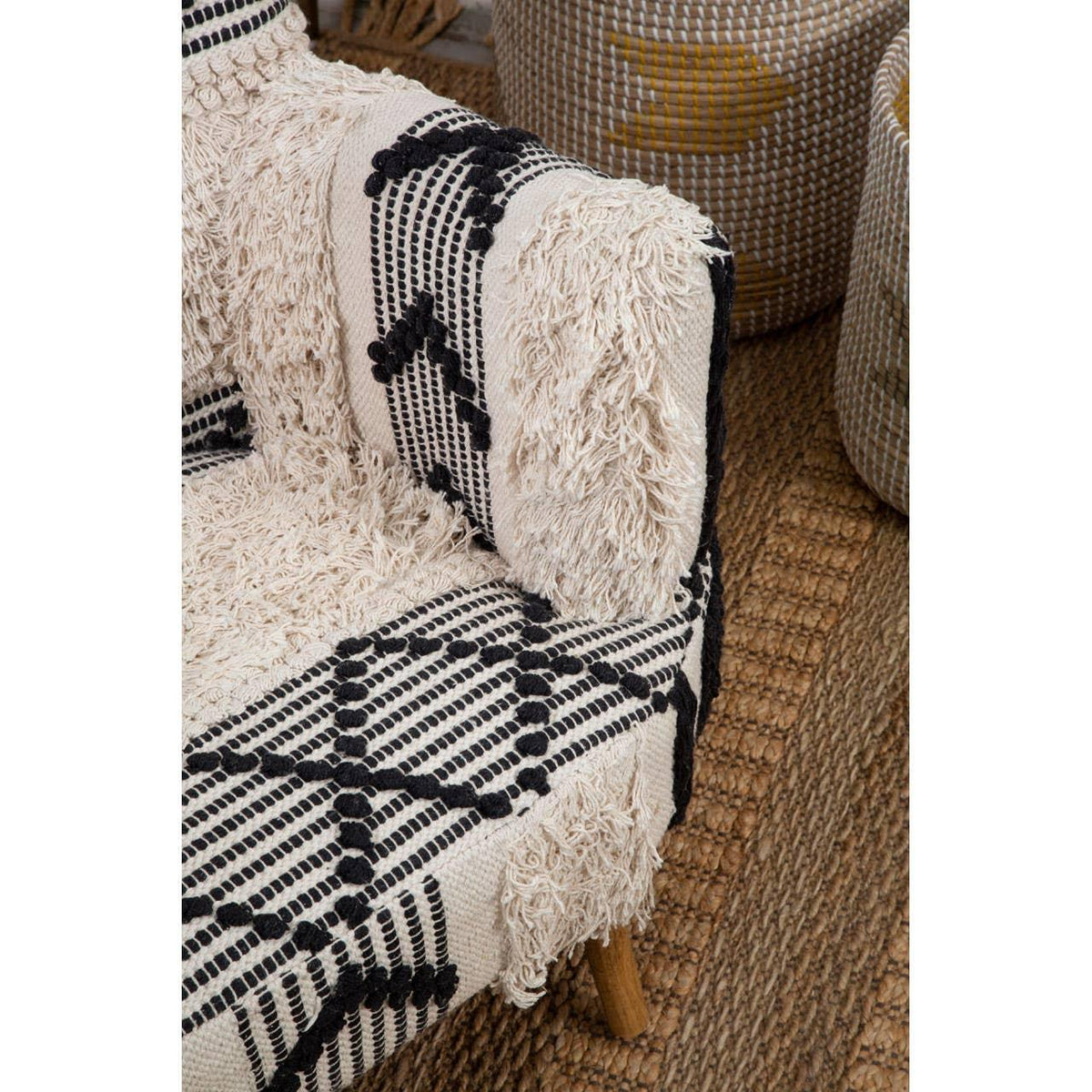 Textured fabric armchair with black and cream geometric pattern on woven jute rug