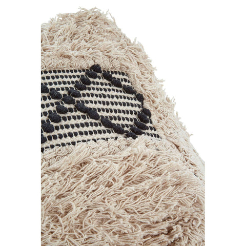 A close-up view of a shaggy pouffe featuring a textured beige surface with black and white woven patterns. The pouffe has a soft, fluffy appearance, highlighting its cozy and inviting design