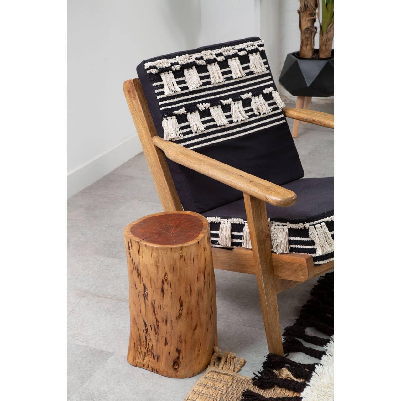 Wooden armchair with black and cream textured cushion beside natural wooden side table