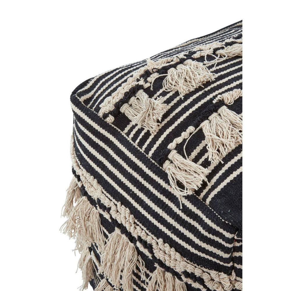 Black and white shaggy pouffe featuring a textured design with fringe detailing and geometric patterns, showcasing a mix of stripes and shapes. The pouffe has a soft, plush appearance, ideal for adding a cozy touch to home decor