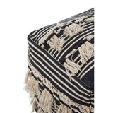 Black and white shaggy pouffe featuring a textured design with fringe detailing and geometric patterns, showcasing a mix of stripes and shapes. The pouffe has a soft, plush appearance, ideal for adding a cozy touch to home decor