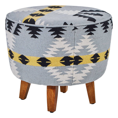Round footstool featuring a colorful Kilim-style fabric with geometric patterns in blue, black, and yellow, supported by four sturdy mango wood legs