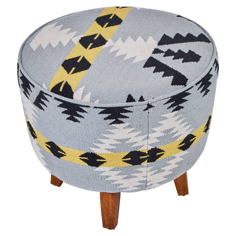 Round footstool featuring a colorful Kilim-style fabric with geometric patterns in blue, black, and yellow, supported by four tapered mango wood legs