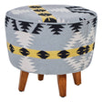 Round footstool featuring a colorful Kilim-style fabric with geometric patterns in blue, black, and yellow, supported by four tapered mango wood legs