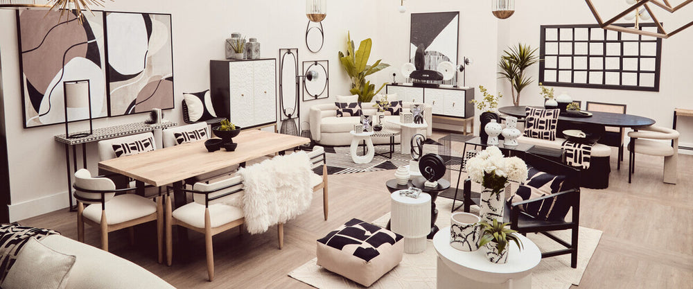 A stylish black and white two-door cabinet is positioned in a modern living space, surrounded by a dining table, chairs, and various decorative items. The cabinet features a sleek design with contrasting colors, complementing the contemporary decor of the room, which includes plants and artwork on the walls