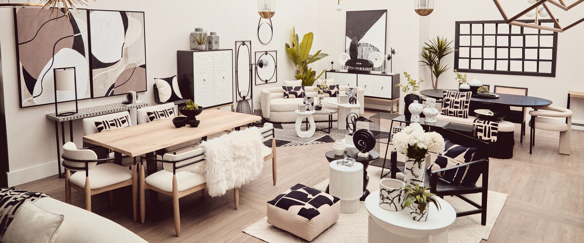 A stylish black and white two-door cabinet is positioned in a modern living space, surrounded by a dining table, chairs, and various decorative items. The cabinet features a sleek design with contrasting colors, complementing the contemporary decor of the room, which includes plants and artwork on the walls