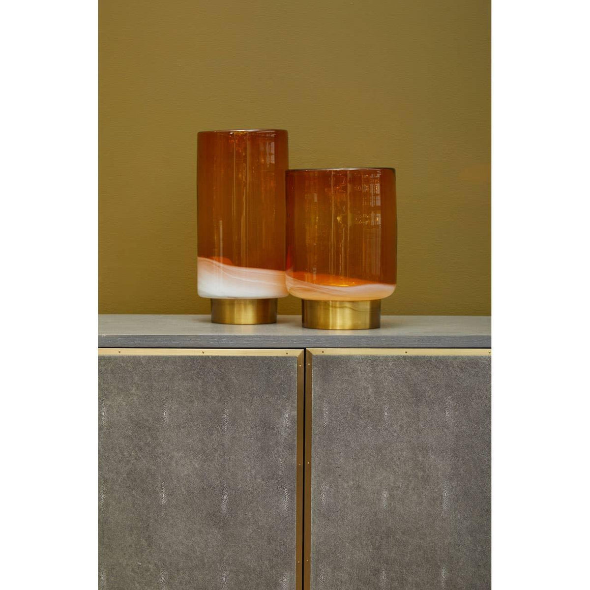 amber and white glass vases with gold bases on modern sideboard