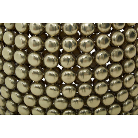 Close-up view of a gold finish stool and side table featuring a textured surface made up of small, round metallic beads arranged in a pattern. The overall design is sleek and modern, showcasing a shiny gold color that reflects light