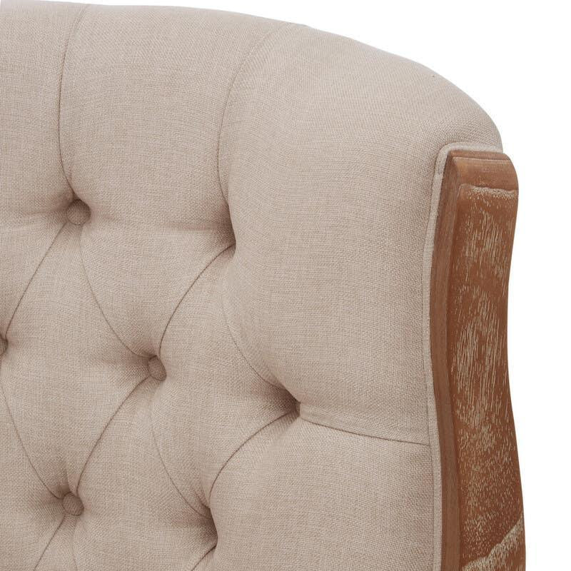 Beige fabric upholstered sofa backrest with button tufting and exposed wooden frame detail