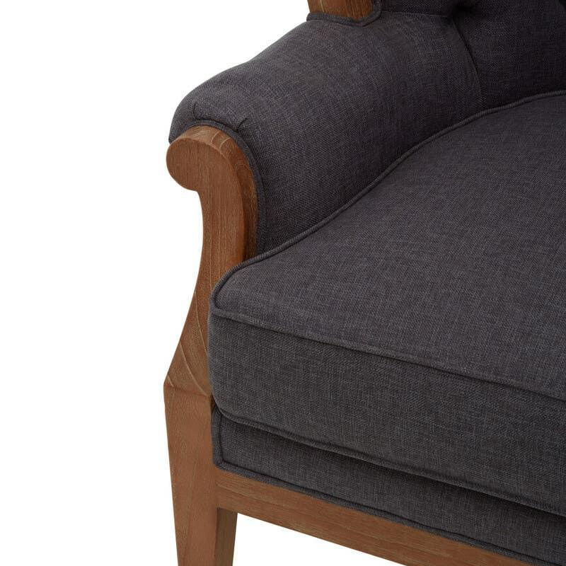 Dark fabric armchair with tufted backrest and wooden arm detail, close-up view