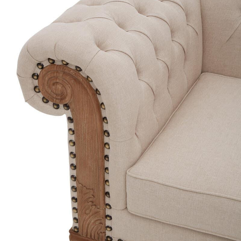 Beige upholstered sofa with deep button tufting and ornate wooden armrest detail