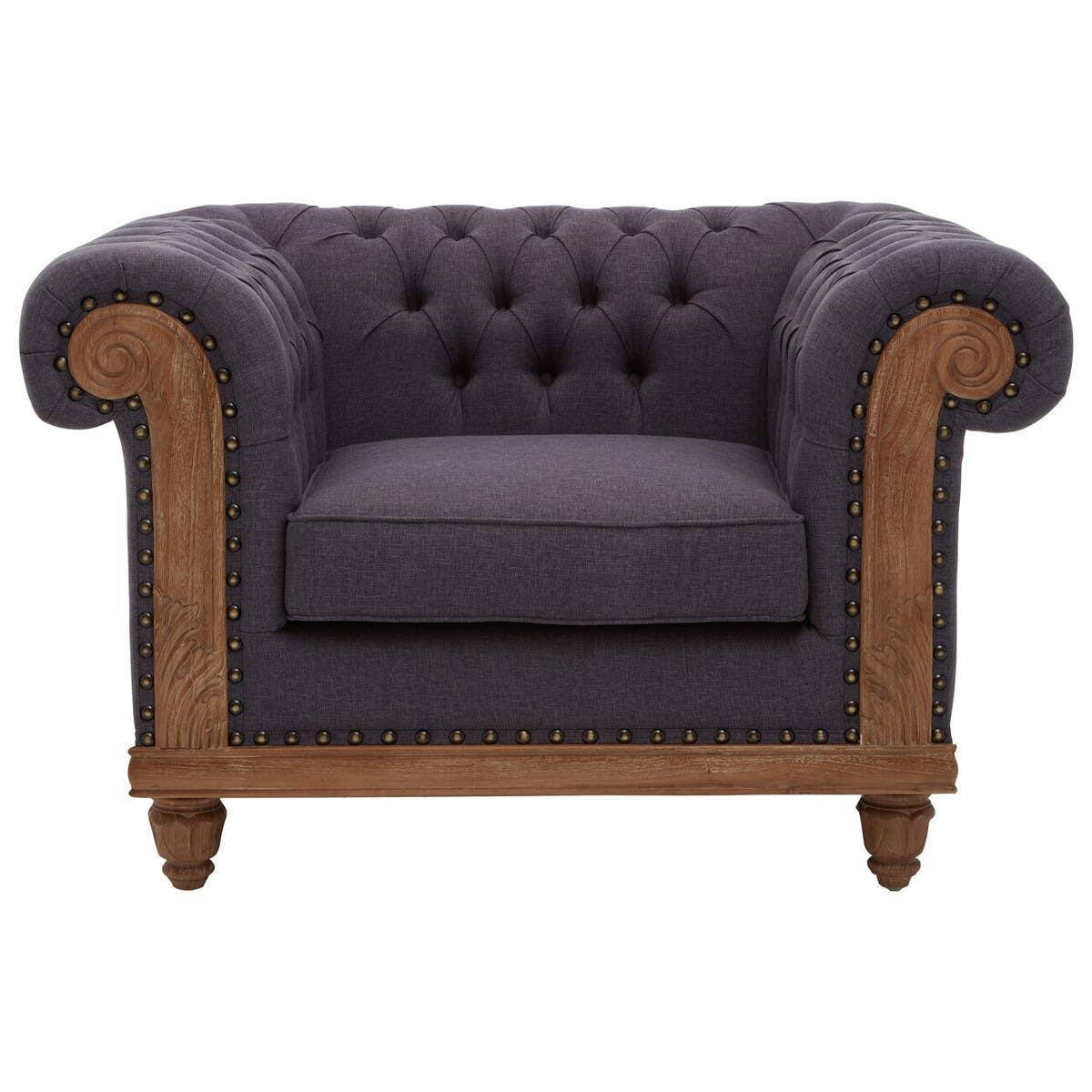 Dark grey Chesterfield armchair with button-tufted back and carved wooden frame, front view