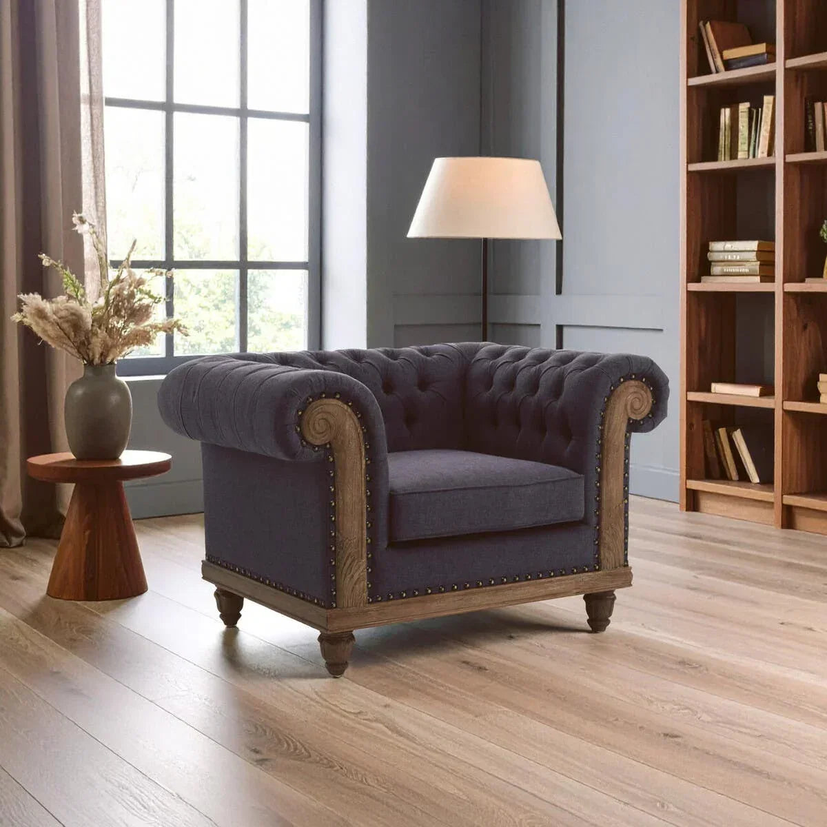Navy blue Chesterfield armchair with wooden trim and button tufting in modern living room