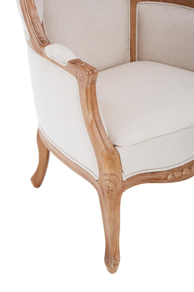 Close up of upholstered armchair with carved wood frame and beige fabric seat