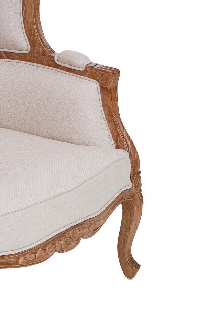 Carved wood armchair with cream upholstered seat and backrest, side angle view