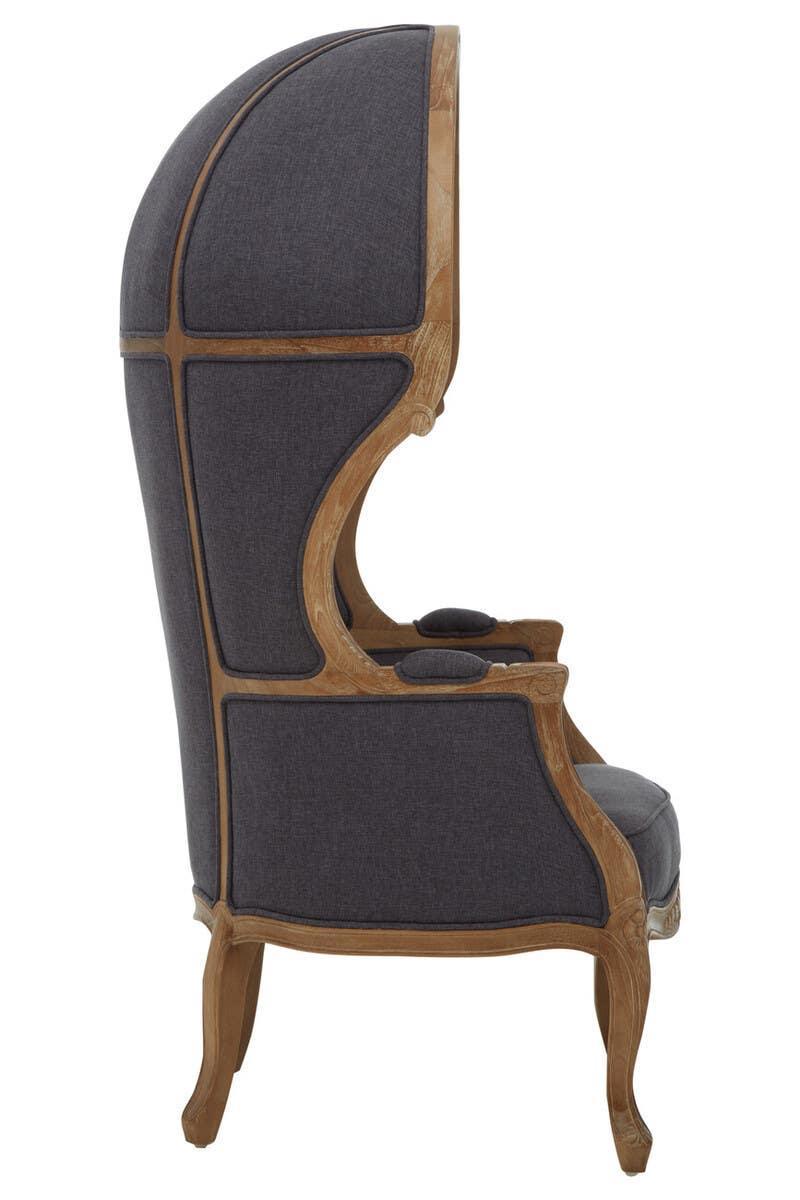 Side view high back armchair with dark fabric upholstery and exposed wood frame