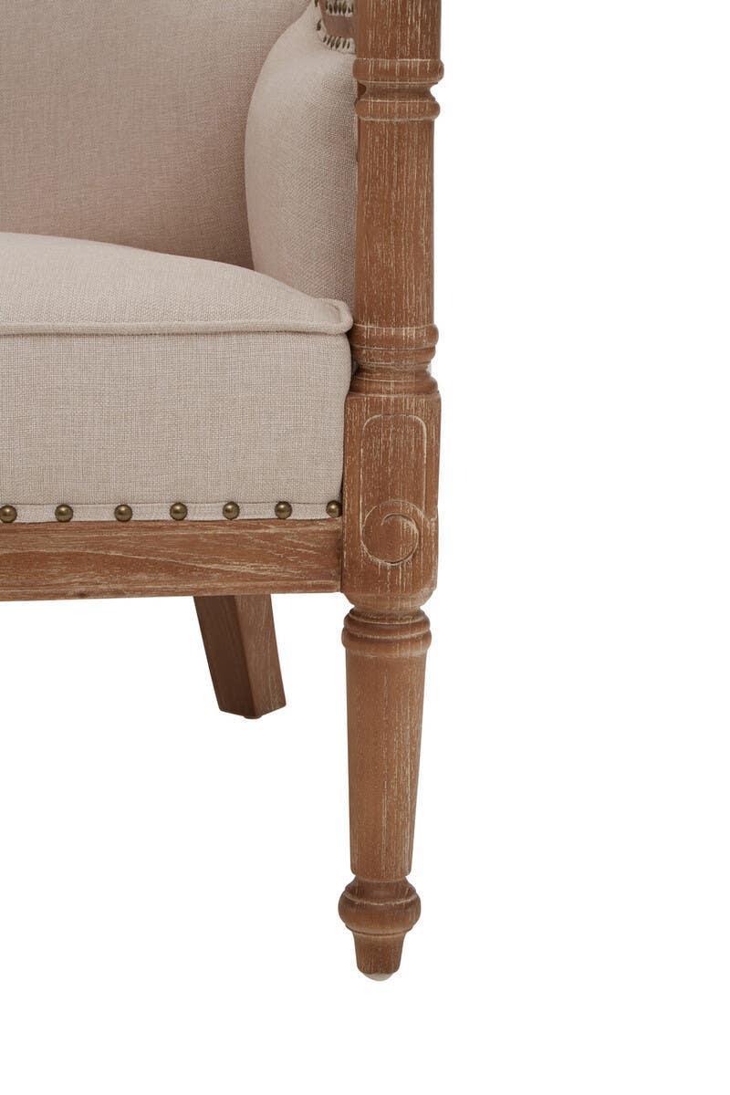 Beige upholstered armchair with turned wooden leg and antique brass stud trim