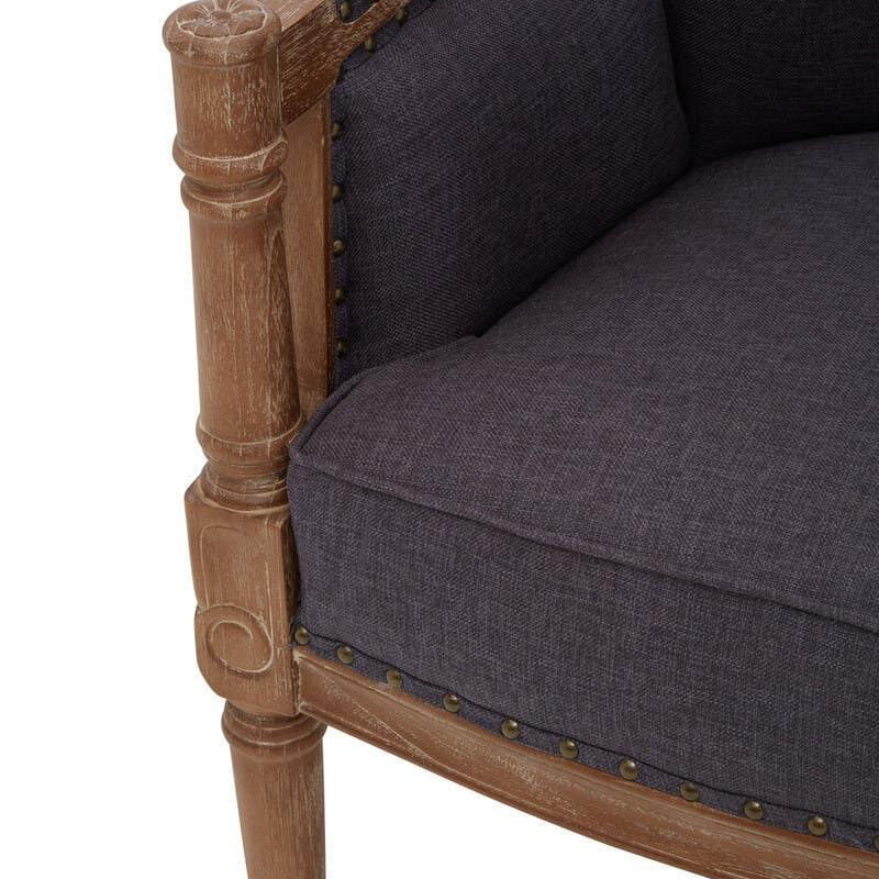 Close view of grey upholstered armchair with wood frame and decorative stud detailing