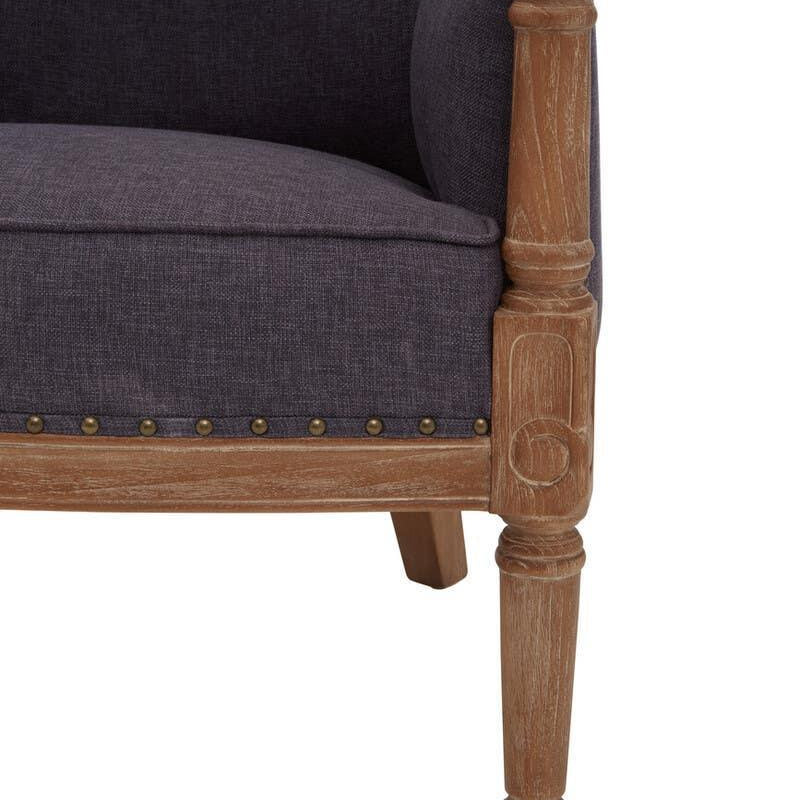 Grey upholstered armchair with carved wooden leg and brass stud detail