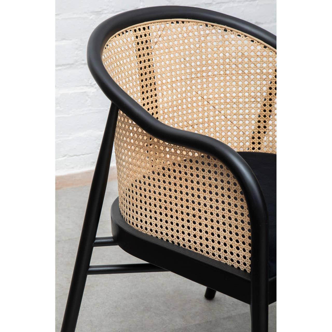 Black wood and cane dining chair with curved backrest on light floor