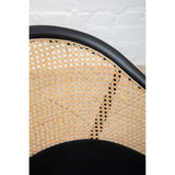 Closeup of rattan dining chair back with black frame against white brick wall