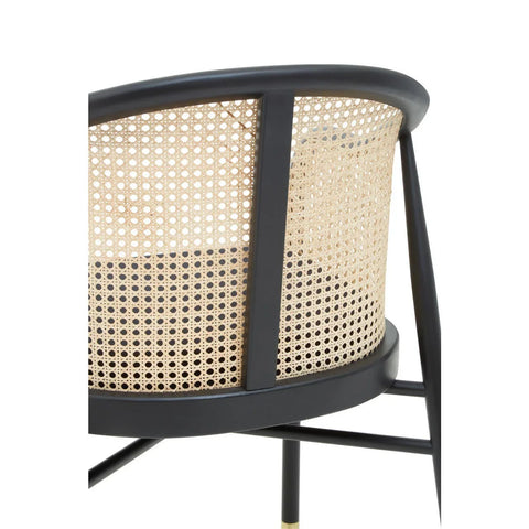 Close up of black rattan accent chair with woven cane backrest and metal frame