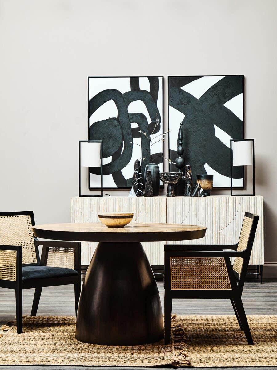 Round wood dining table with black base and rattan dining chairs in modern dining room