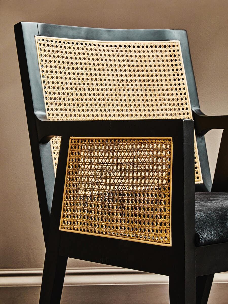 Black wooden accent chair with cane rattan back and side panels, velvet seat detail