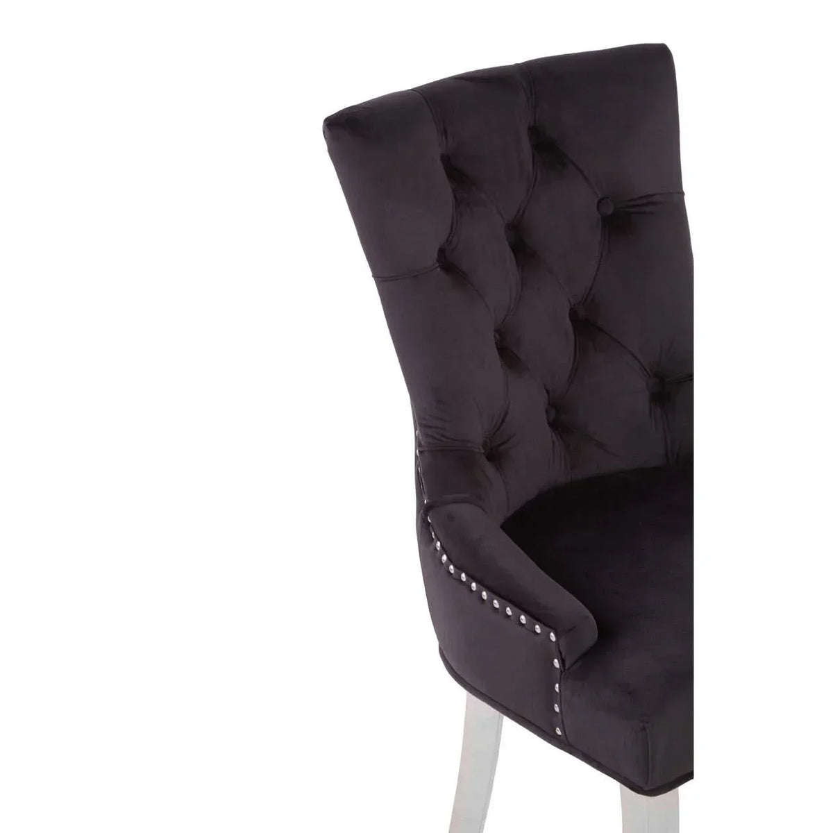 Black velvet dining chair with tufted back and silver stud details, partial side view