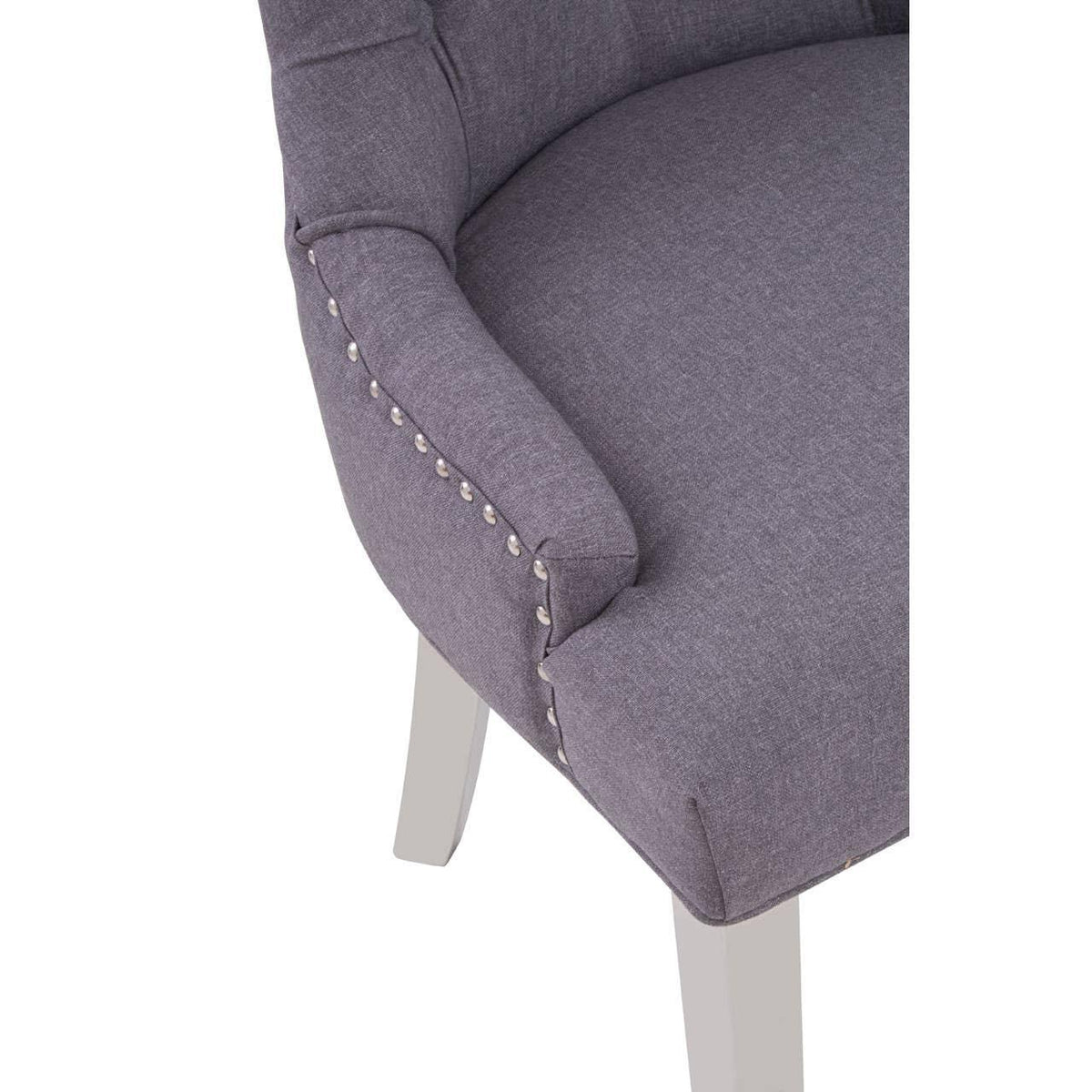 Grey upholstered dining chair with silver stud detailing and white wooden legs
