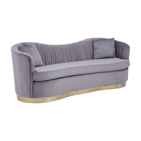 A three-seat sofa upholstered in soft grey pleated velvet, featuring a curved backrest and plush cushions. The base is elegantly designed with a gold trim, adding a touch of sophistication