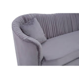 Grey pleated velvet sofa featuring a curved backrest and a plush seat, accompanied by a matching cushion. The fabric has a soft texture, and the pleats add a stylish detail to the overall design