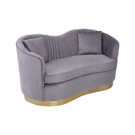 A two-seat sofa upholstered in soft grey pleated velvet, featuring a curved backrest and two matching cushions. The base is elegantly finished in gold, adding a touch of sophistication to the design