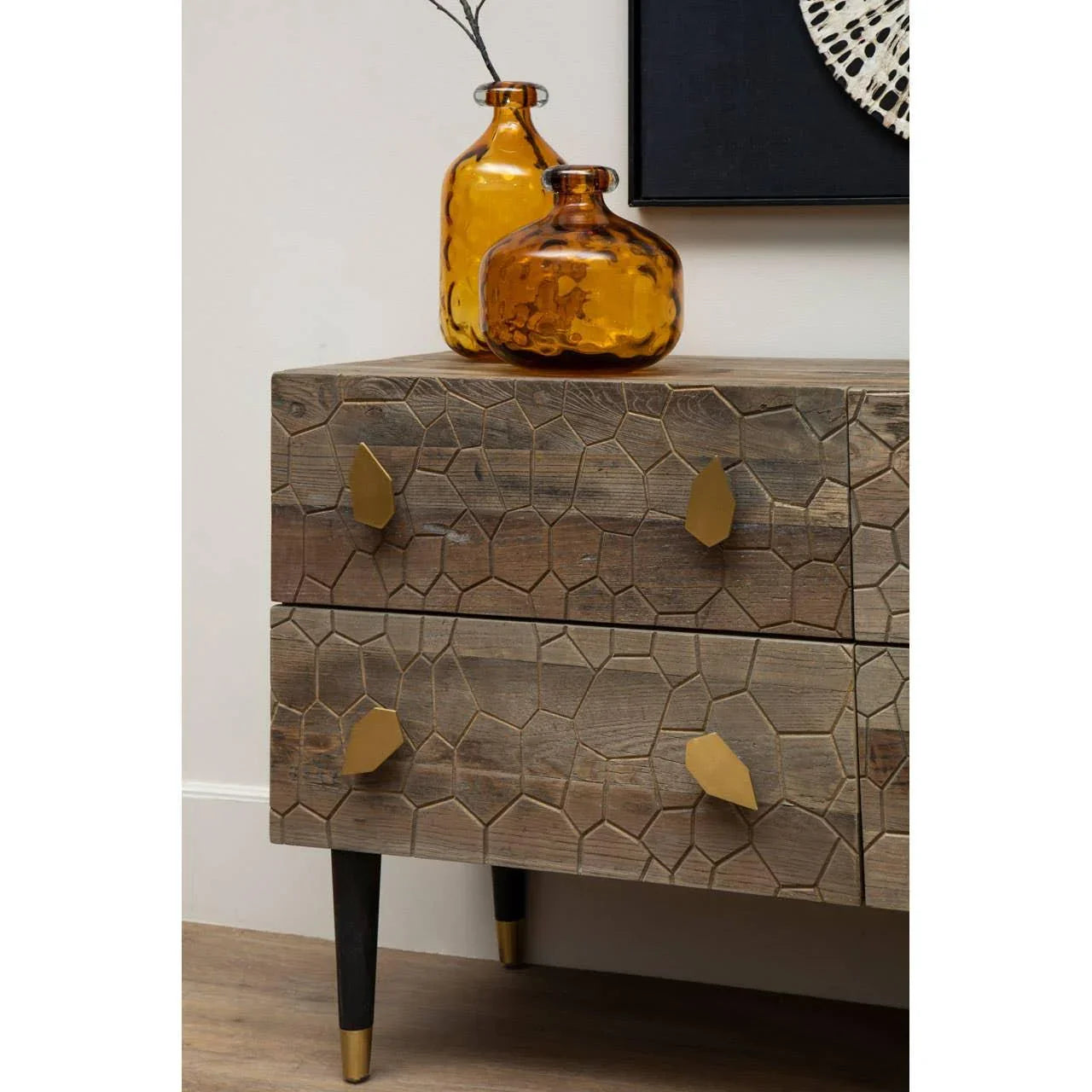 carved wood chest of drawers with gold handles and amber glass vases on top