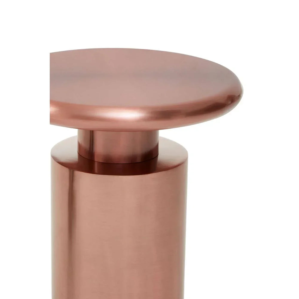 Close-up of metallic copper side table with round top and cylindrical base