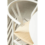 White wooden dining chair with woven seat beside round table on striped rug