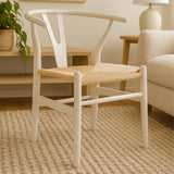 White dining chair with curved back and woven natural seat on beige rug in living room