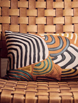 Tan leather woven chair with geometric embroidered cushion in earthy tones