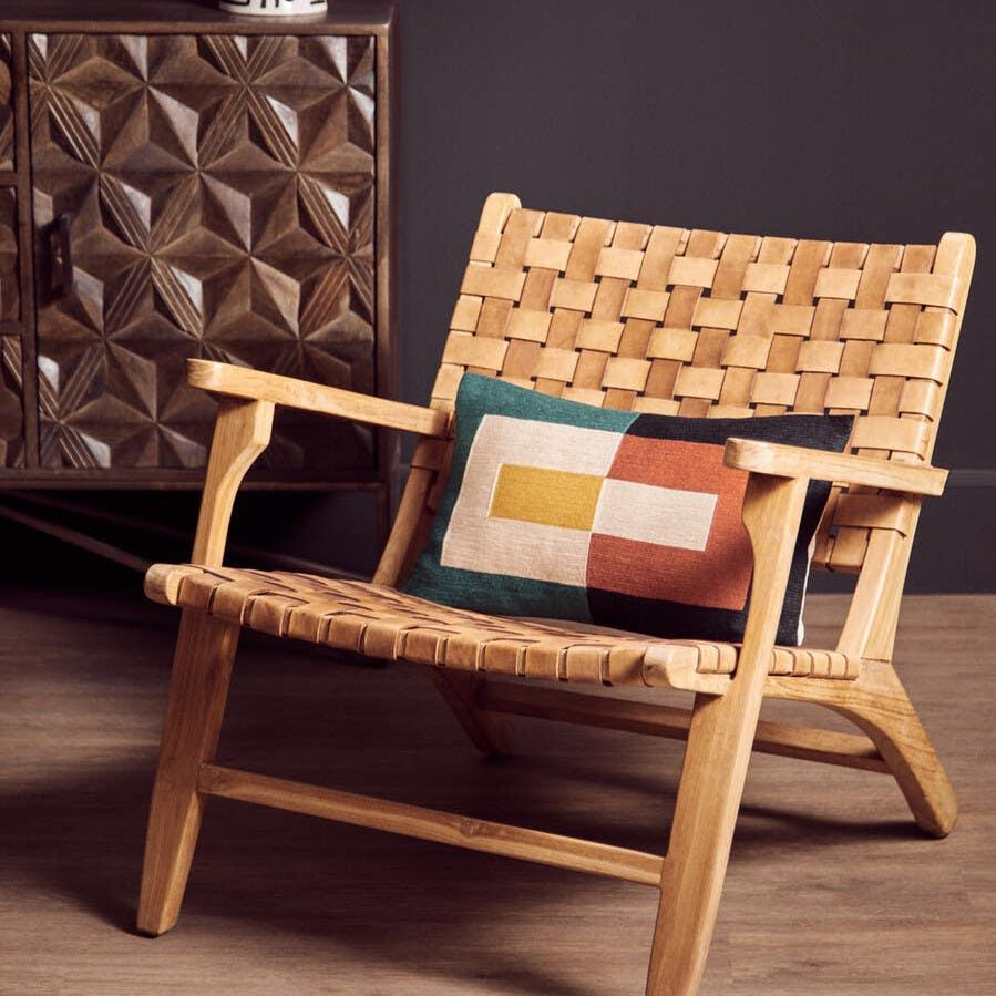 Light wood lounge chair with woven leather seat and geometric cushion in modern living room