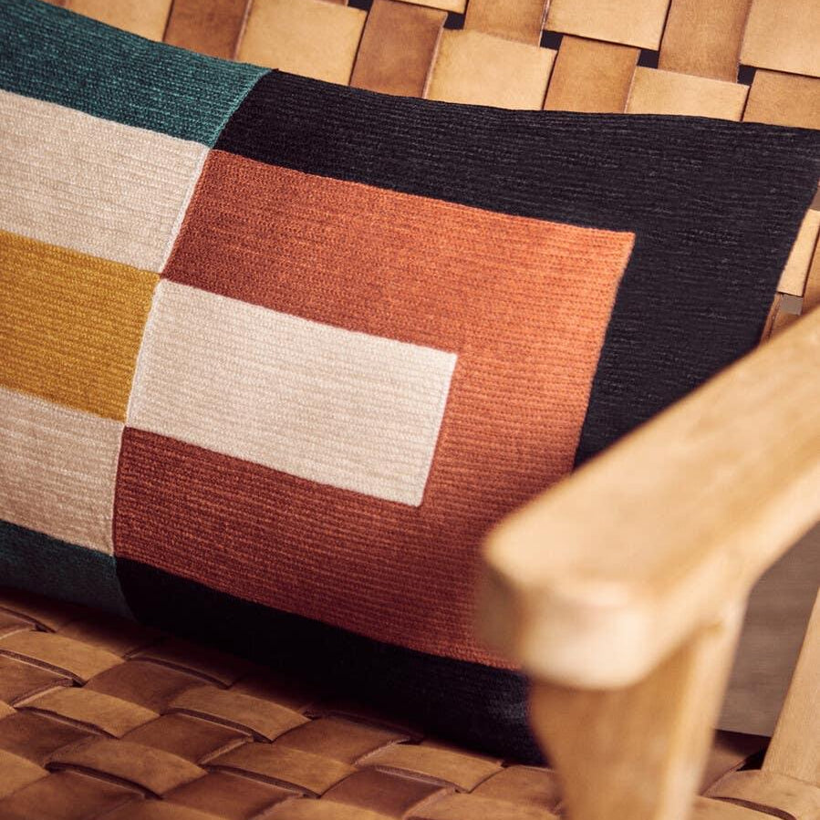 Woven leather armchair with geometric cushion in orange, green, cream and black